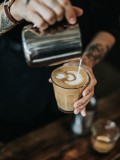 barrista pouring milk in coffee